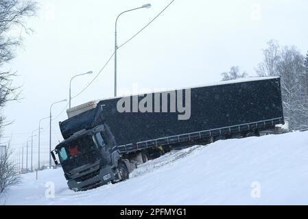 Main truck with a semi-trailer flew off the track in heavy snowfall Stock Photo