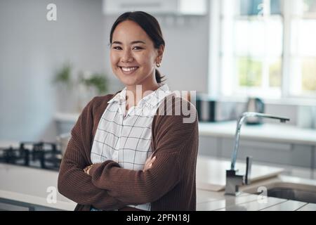 Feeling relaxed at home. Portrait of a young woman standing with her arms crossed in the kitchen at home. Stock Photo