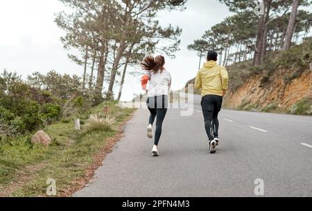 Reaching new heights together. Full length shot of two unrecognizable athletes bonding together during a run outdoors. Stock Photo