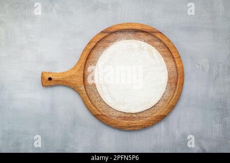 Empty wooden pizza platter set up on grey concrete. Pizza tray on grey concrete background flat lay and copy space. Stock Photo