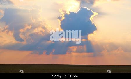 sunset, the rays of which break through the clouds creating a silhouette and contour of the clouds Stock Photo