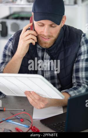 young male technician checking refrigerator with screwdriver Stock Photo