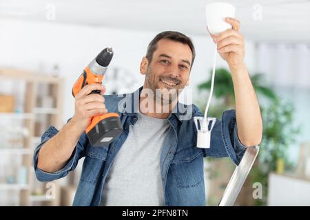 electrician fitting a ceiling light Stock Photo