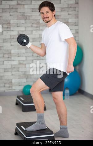 handsome guy with a sporty build doing lunges with dumbbells Stock Photo