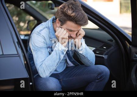 stressed man sitting on drivers seat of parked car Stock Photo