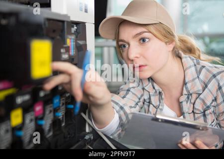 female technician checking printer Stock Photo