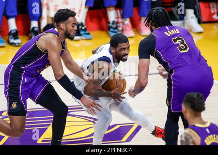 Los Angeles, United States. 17th Mar, 2023. Dallas Mavericks guard Kyrie Irving (C) drives between Los Angeles Lakers guard Troy Brown Jr. (L) and forward Anthony Davis (R) during an NBA basketball game at Crypto.com Arena, Friday, March 17, 2023, in Los Angeles. Credit: SOPA Images Limited/Alamy Live News Stock Photo