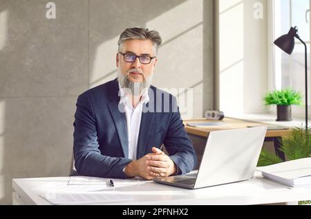 Mature business man working at the desk on his workplace at office, looking confident at camera. Stock Photo