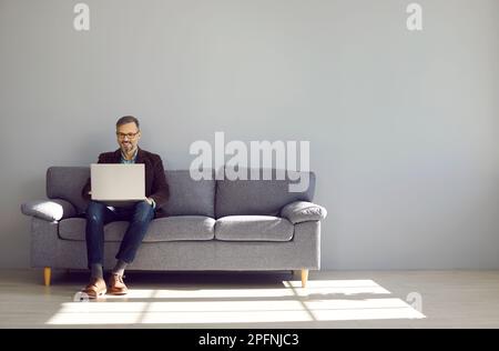 Mature businessman sitting on sofa working with laptop Stock Photo