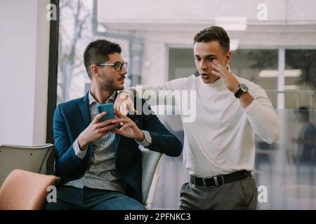 Two well dressed and handsome business partners talking at the office Stock Photo