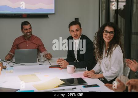 Close up of business people smiling and listening to his colleague explaining something while sitting at the co working space Stock Photo