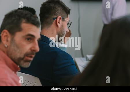 Close up of business man with dark blue suit and glasess looking down while sitting at the office desk Stock Photo