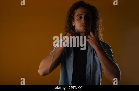 Curly haired man posing and making his jacket in the studio Stock Photo