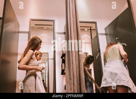 Two pretty best friends standing in the changeing room and trying clothes Stock Photo