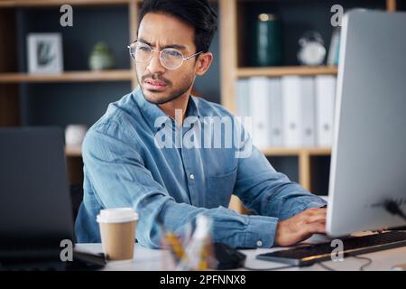 Serious, business man working on computer, laptop and software development, digital research and information technology. Coding developer or asian Stock Photo
