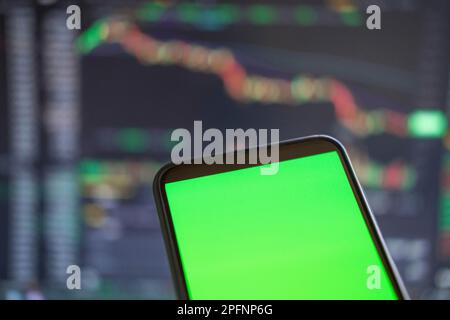 Black phone with blank mockup screen on rising stock graph. Closeup hand showing smartphone isolated green display. Online banking, Fund App use. Fina Stock Photo