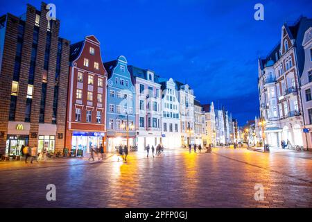 Rostock, Germany. 13th Mar, 2023. View in the so-called blue hour from Universitätsplatz into Kröpeliner Strasse with the residential and commercial buildings in the Hanseatic style. Credit: Jens Büttner/dpa/Alamy Live News Stock Photo