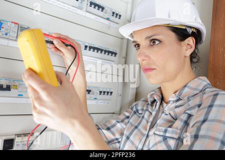 female electrical worker installing a fuse box Stock Photo