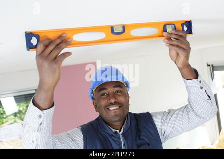 builder taking measures with spirit level on the ceiling Stock Photo