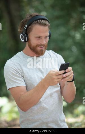 man outdoors using smartphone and wearing headphones Stock Photo