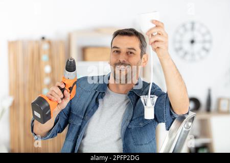 man is drilling the ceiling to place a lamp Stock Photo