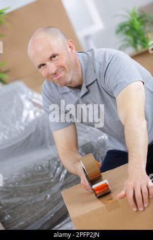 young caucasian man using duct tape for packing box Stock Photo