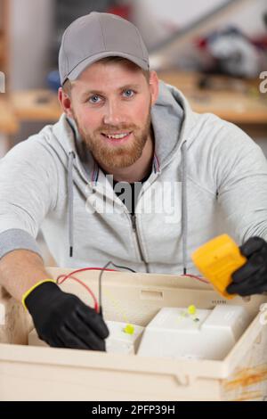 electrician testing electricity box with multimeter Stock Photo