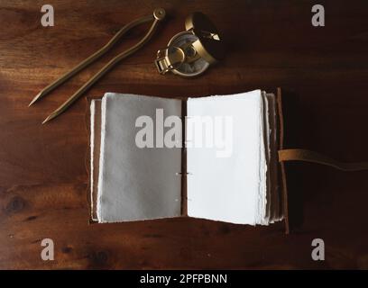 Vintage leather journal or diary on a black table with a compass next to it Stock Photo