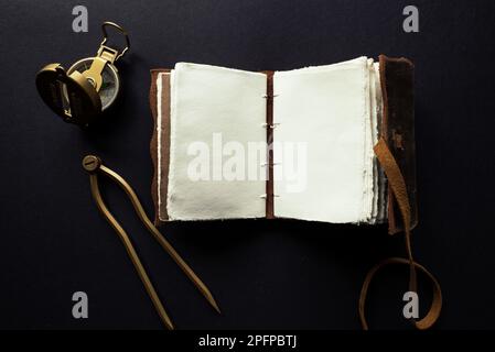 Vintage leather journal or diary on a black table with a compass next to it Stock Photo