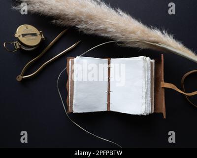 Vintage leather journal or diary on a black table with a compass next to it Stock Photo
