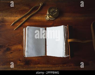 Vintage leather journal or diary on a black table with a compass next to it Stock Photo