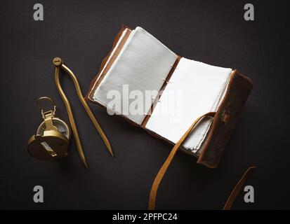 Vintage leather journal or diary on a black table with a compass next to it Stock Photo