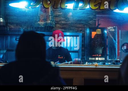 A man wearing a red baseball cap working in a diner at night Stock Photo