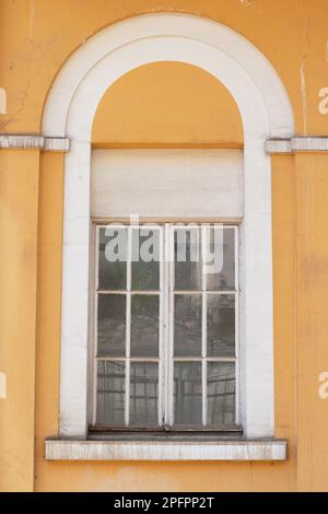The white colored window of a yellow building, the grilles on the window. Stock Photo