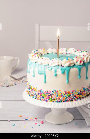 Birthday cake with white drip icing, sprinkles and colorful birthday ...