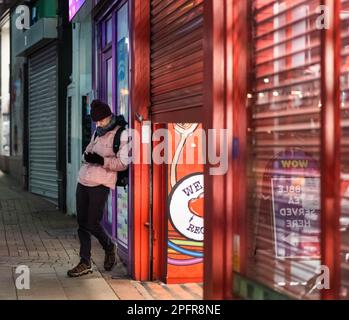 A young male leaning against the wall and using his smartphone Stock Photo