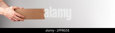 Hand holding cardboard box, parcel, order package on long web banner. Stock Photo