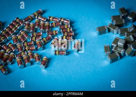 SMD diodes and smd ceramic capacitors, on a table with a blue background, electronic components Stock Photo