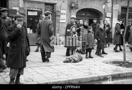In the early stages of WW2 the Jews in nazi occupied europe were rounded up and forced into crowded ghettoes. When the decision was made to kill them all they were deported to extermination centres to be murdered. This image shows the body of a dead or dying child lies on the streets of the Warsaw Ghetto during WW2. Bild 101I-134-0771A-39 / Zermin / CC-BY-SA 3.0 Stock Photo