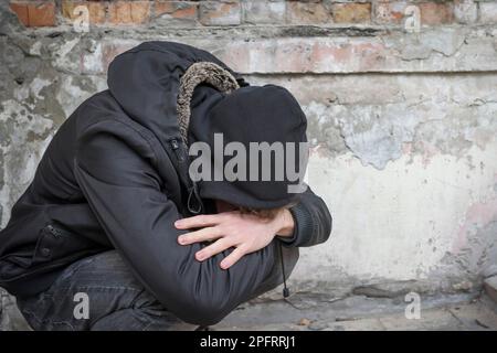 A young drug addict experiencing a drug addiction crisis, sitting in an ...