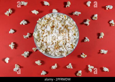 Plate of popcorn on a red colored background. Cinema and entertainment concept. Top view Stock Photo