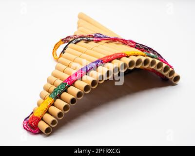 Pan flute with colorful band around against white background. Stock Photo