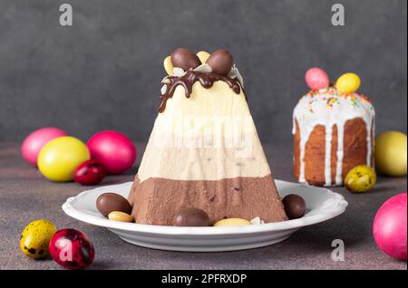 Traditional Easter curd dessert made of three types of chocolate - white, milk and dark and as well Easter cake and colorfull eggs Stock Photo