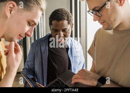 A young developer gives new project tasks to his partners. Business people are discussing a new business project in the office. Coding technologies Stock Photo
