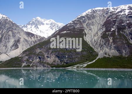 The springtime view of tall mountains and calm water with ice in Glacier Bay national park (Alaska). Stock Photo