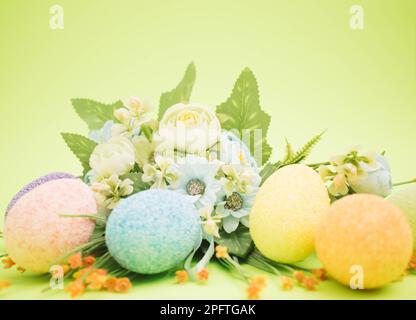 Bouquet made of easter eggs and colorful flowers on a bright green background Stock Photo