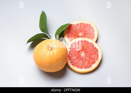 Ripe grapefruits and plant branch on light background Stock Photo