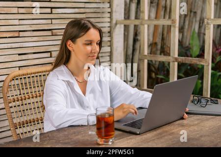 Freelancer woman using laptop computer sit in office typing on laptop. Stock Photo