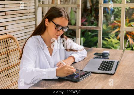Woman designer using digital tablet and laptop computer in summer office Stock Photo