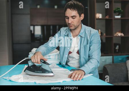 Home working, a man ironing his shirts at home Stock Photo